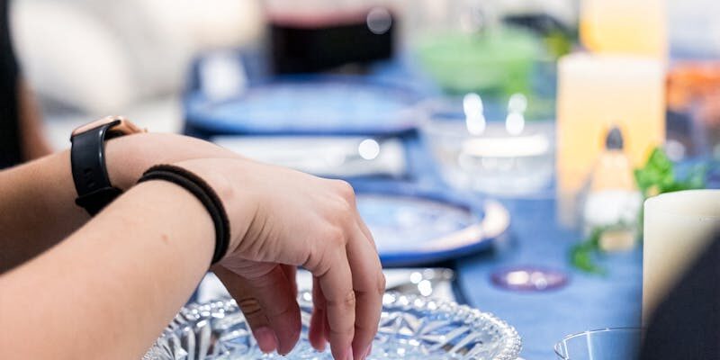 A close-up of hands dipping in a bowl at a Passover Seder table setting, emphasizing tradition.