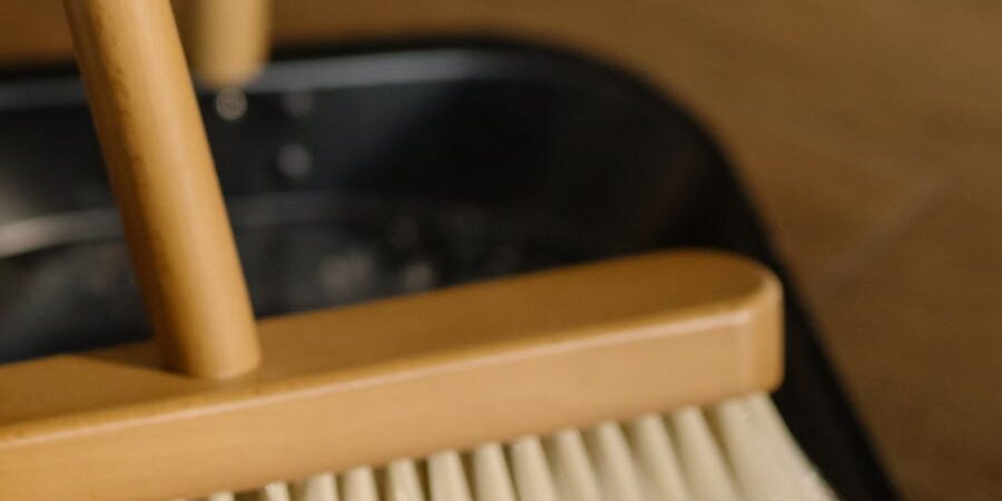 Detailed image of a broom and dustpan used for cleaning wooden floors at home.